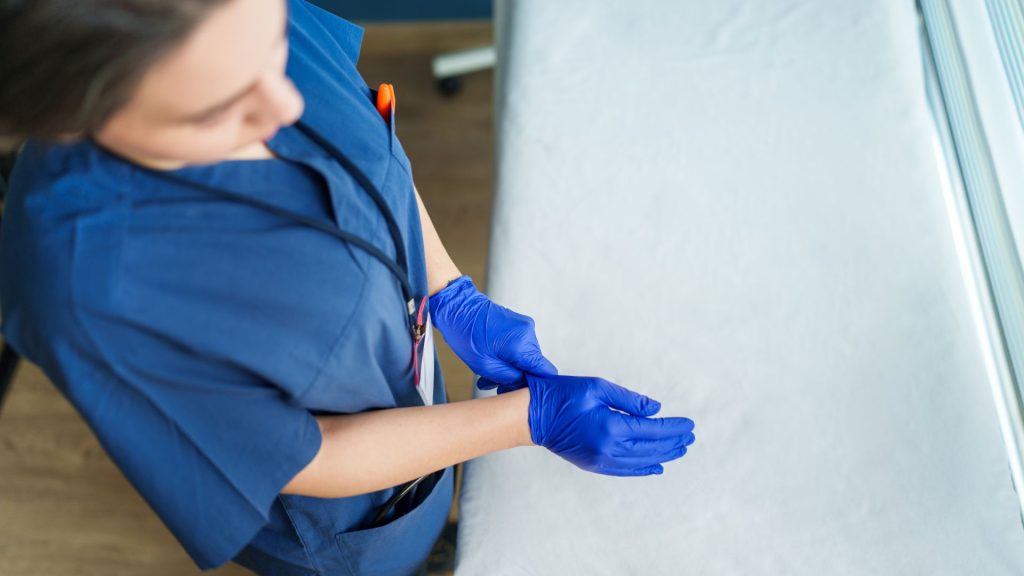 HPPES - nurse donning nitrile gloves. procurement reduce supply chain risk for nitrile gloves